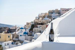 a bottle of wine and two glasses sitting on a ledge at Three Domes Oia - an Iconic Collection in Oia