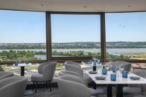 a dining room with tables and chairs and large windows at DoubleTree by Hilton Washington DC – Crystal City in Arlington
