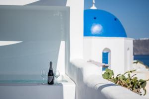 a bottle of wine sitting on a ledge with wine glasses at Three Domes Oia - an Iconic Collection in Oia