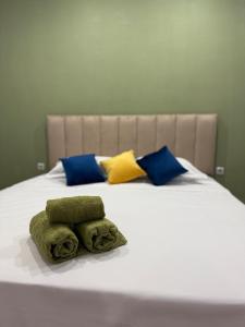 a white bed with blue and yellow pillows on it at Tkacheva 14 in Pavlodar
