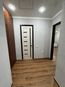 an empty room with a door and a wooden floor at Tkacheva 14 in Pavlodar +2 photos