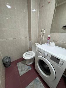 a bathroom with a washing machine and a toilet at Tkacheva 14 in Pavlodar