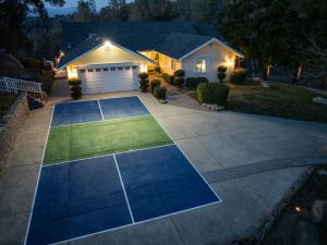 a driveway with a tennis court in front of a house at Yosemite Bass Lake VIEWS, 2 Homes, Games, Hot Tub in Coarsegold