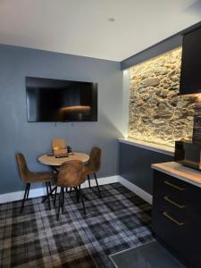 a dining room with a table and chairs and a tv at Lochview Apartment in Tarbet