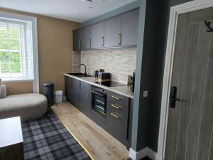 a kitchen with black cabinets and a couch in a room at Lochview Apartment in Tarbet