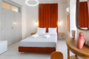 a bedroom with a bed with orange curtains and a table at Arsenale di Nafplio Rooms in Nafplio