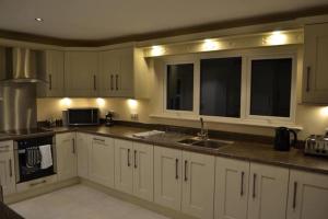 a kitchen with white cabinets and a sink at Glendarragh Cottage in Cushendall
