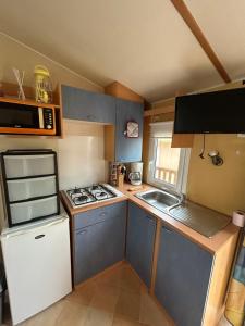 Una pequeña cocina con estufa y refrigerador. en La Cigale, en Le Grau d'Agde 22 fotos más