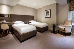 a hotel room with two beds and a table and a chair at Radisson Blu Hotel, London Bloomsbury in London