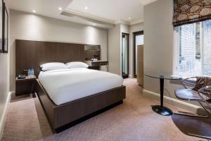 a bedroom with a large bed and a table at Radisson Blu Hotel, London Bloomsbury in London