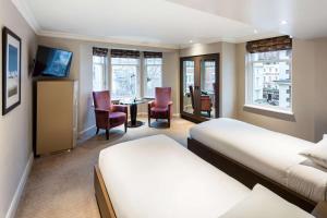 a hotel room with two beds and a table and chairs at Radisson Blu Hotel, London Bloomsbury in London