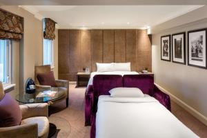 a hotel room with two beds and a table at Radisson Blu Hotel, London Bloomsbury in London