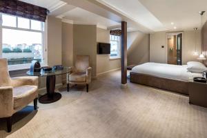 a hotel room with a bed and a desk and chair at Radisson Blu Hotel, London Bloomsbury in London