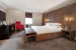 a hotel room with a large bed and a red chair at Radisson Blu Hotel, London Bloomsbury in London