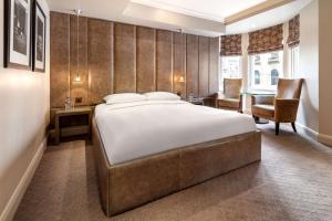 a bedroom with a large bed and a desk and chairs at Radisson Blu Hotel, London Bloomsbury in London