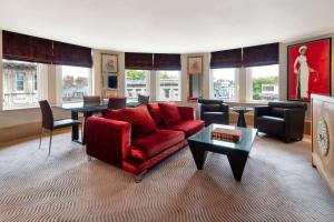 a living room with a red couch and a table at Radisson Blu Hotel, London Bloomsbury in London