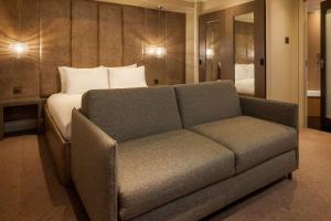 a couch in front of a bed in a room at Radisson Blu Hotel, London Bloomsbury in London