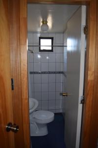 a small bathroom with a toilet and a window at Hostal Buenaventura in Valdivia