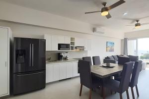 cocina con nevera negra, mesa y sillas en Costa Paraíso D-20 2-Recamaras, en Bucerías