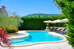 a swimming pool in a yard with chairs and an umbrella at Villa Zita u Svicima for 10 people with jacuzzi & sauna in Central Istria in Pićan