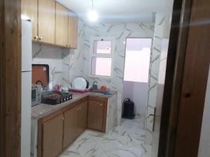a kitchen with marble walls and wooden cabinets at Aicha appartement 2 in Meknès