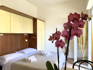 a bedroom with a bed and a vase with purple flowers at Residence Carioca in Rimini