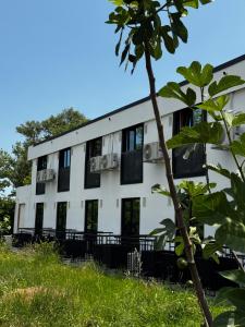 ein weißes Gebäude mit schwarzen Fenstern und einem Baum in der Unterkunft Belvedere Costinesti in Costinești