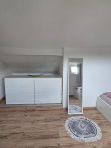a white bedroom with a bed and a mirror at Schumacher Ferienwohnung in Netphen
