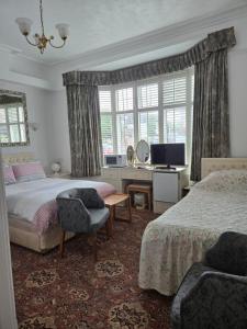 a bedroom with two beds and a desk and a television at Shoreline Accommodation in Bournemouth