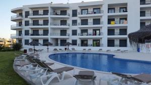 a hotel with a swimming pool in front of a building at Vista das Ondas Apartamento 205 B2 - Olhos de Agua in Albufeira