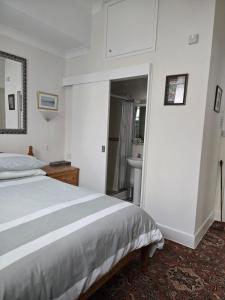 a white bedroom with a bed and a bathroom at Shoreline Accommodation in Bournemouth