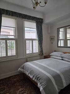 a bedroom with a large bed and two windows at Shoreline Accommodation in Bournemouth