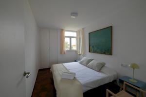 a bedroom with a white bed and a window at Apartamento con piscina in Torredembarra +26 photos