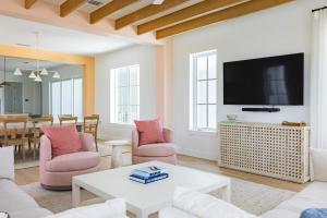 a living room with pink chairs and a flat screen tv at New Waterfront Home - Dreamside House in Key West