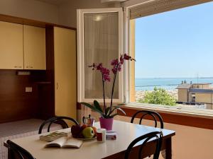 een tafel met een vaas met bloemen en een raam bij Residence Carioca in Rimini
