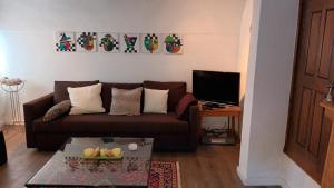 a living room with a brown couch and a television at Urgemütlicher Winkelhof "La ferme von 1634" mit Terrasse in Simmerath