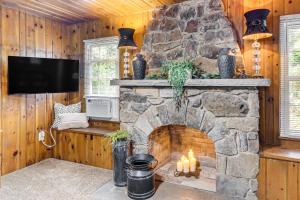 a living room with a stone fireplace with candles at Less Than 1 Mi to Raystown Lake Family-Friendly Cottage! in Huntingdon