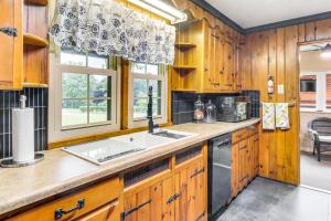 a kitchen with wooden cabinets and a sink and a window at Less Than 1 Mi to Raystown Lake Family-Friendly Cottage! in Huntingdon