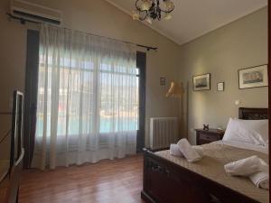 a bedroom with a bed and a large window at West Pool House in Kineta +7 photos