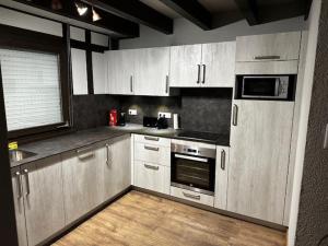 a kitchen with white cabinets and a wooden floor at Cottage des Cîmes in Climbach