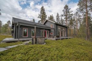 a black house on top of a green field at 2-Wing Villa 4BR, 2 SkiPasses, Ylläs & Nature View in Ylläsjärvi