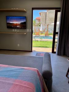 a bedroom with a tv and a bed and a sliding glass door at Jangadas do Toque Milagres Flats no Térreo in São Miguel dos Milagres