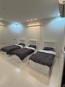 three beds in a room with a wall at شقق روابي الباحه in Al Jith