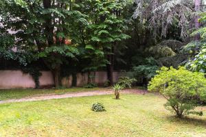 un jardín con árboles, césped y una pared en Rez de jardin relaxant et calme, en Neuilly-sur-Seine