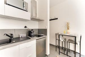 Una cocina blanca con fregadero y encimera. en Rez de jardin relaxant et calme, en Neuilly-sur-Seine