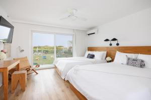 two beds in a room with a desk and a window at Hero Beach Club in Montauk
