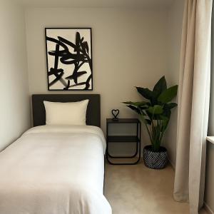 a bedroom with a white bed and a potted plant at Lilla Gutebagge Logi in Visby +8 photos