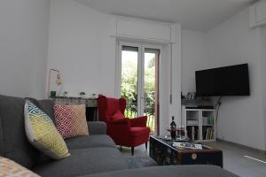 a living room with a gray couch and a red chair at Il Cortiletto - Cozy Apt Brand New Equipped Private Garden - BBQ in Como