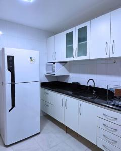 a kitchen with white cabinets and a white refrigerator at RefugioBacutia- Prédio FRENTE MAR Bacutia- 6 pessoas- 3 Quartos com AR sendo 1 suite - varanda- sala de estar e jantar Ampla -Piscina e Sauna no Prédio in Guarapari +88 photos