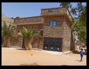 a man standing in front of a brick house at Maison Manour chambre 'soft breeze' in Mbour